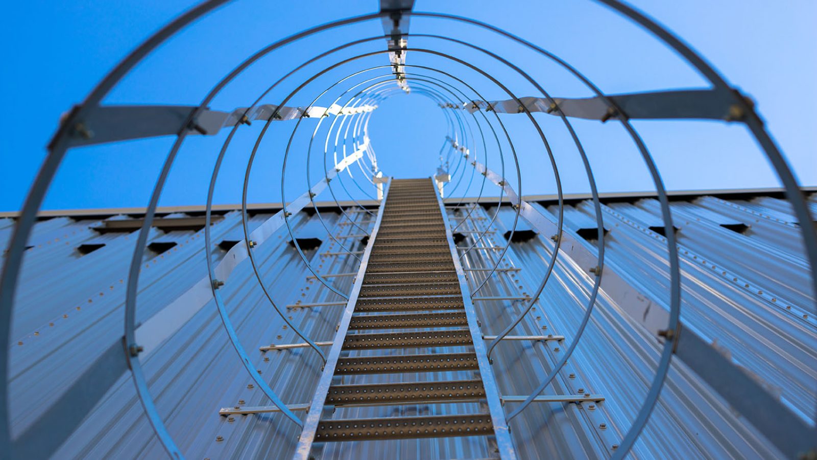 Vertical metal staircase to the roof of the hangar. Staircase surrounded by a protective frame.